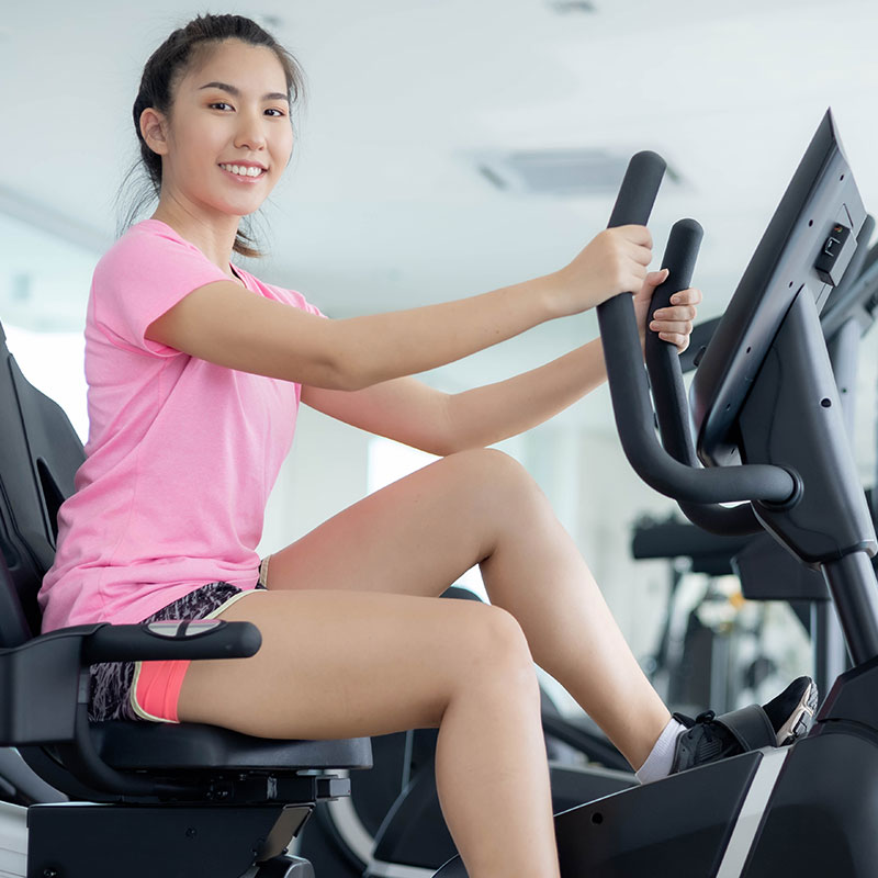 A smiling woman working out on a gym bike